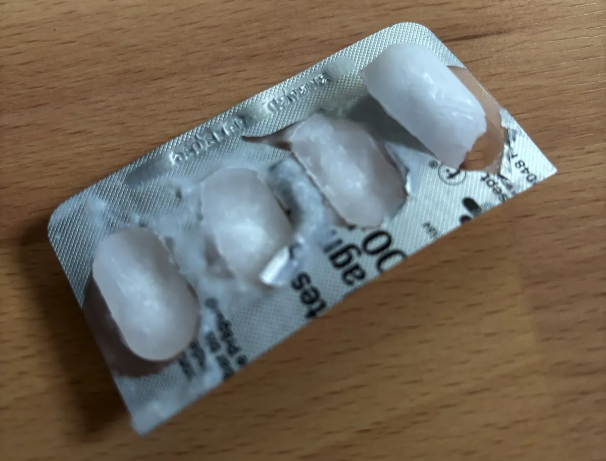 The same blister pack after freezing, the foil partly peeled back and the oil cubes frosted over.